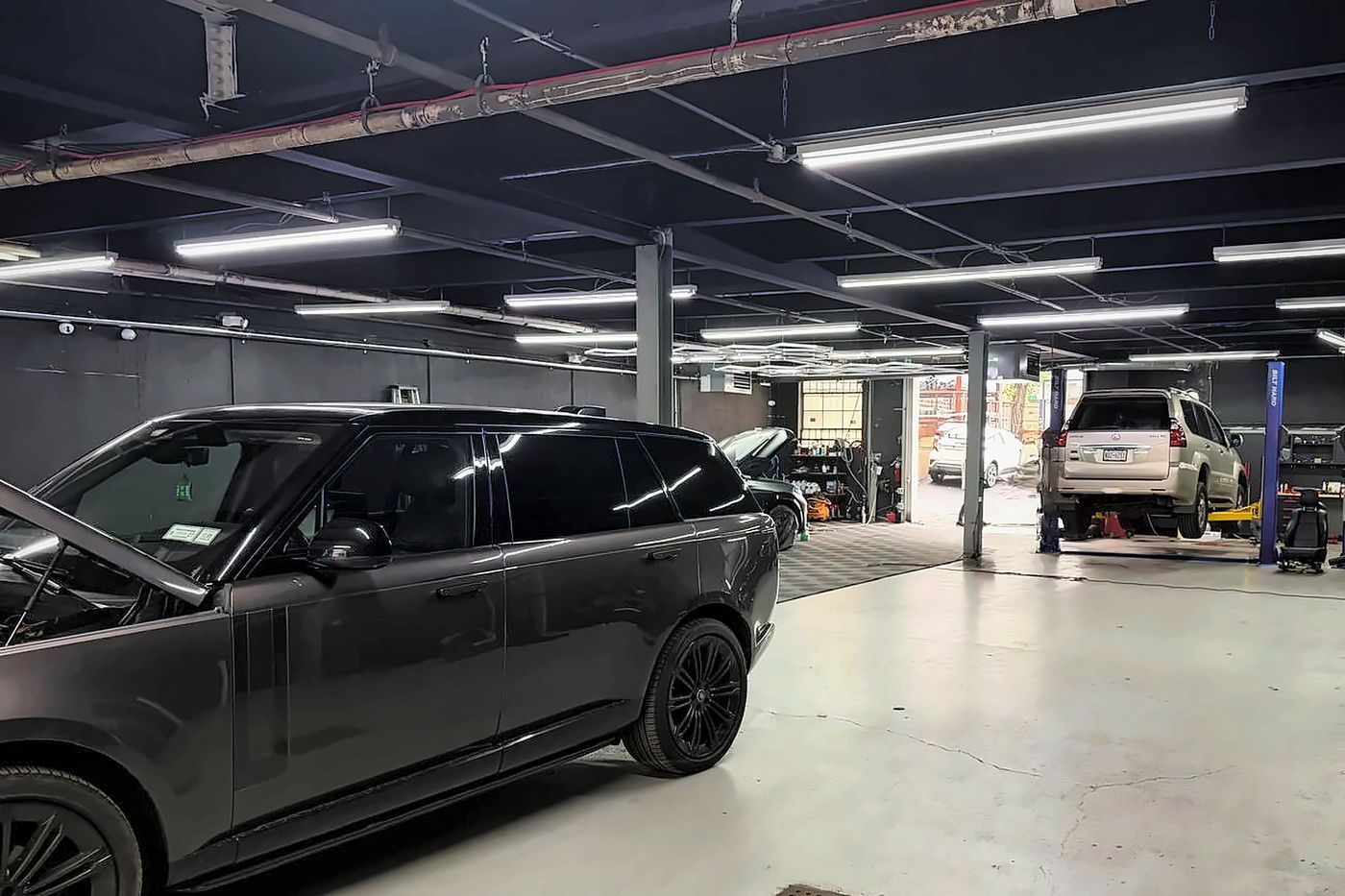 Lift bay with hood open for service at Triforce Auto Repair